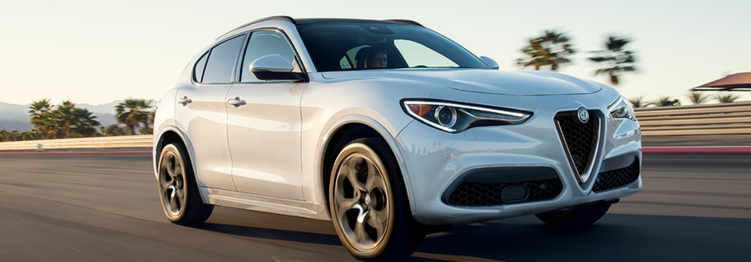 2022 Alfa Romeo Stelvio driving down a road at sunset