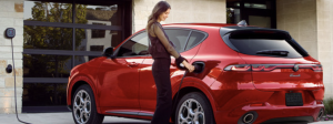A woman charges a red 2025 Alfa Romeo Tonale PHEV.