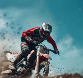 motocross_rider_in_red_gear_racing_on_dirt_track_under_blue_sky