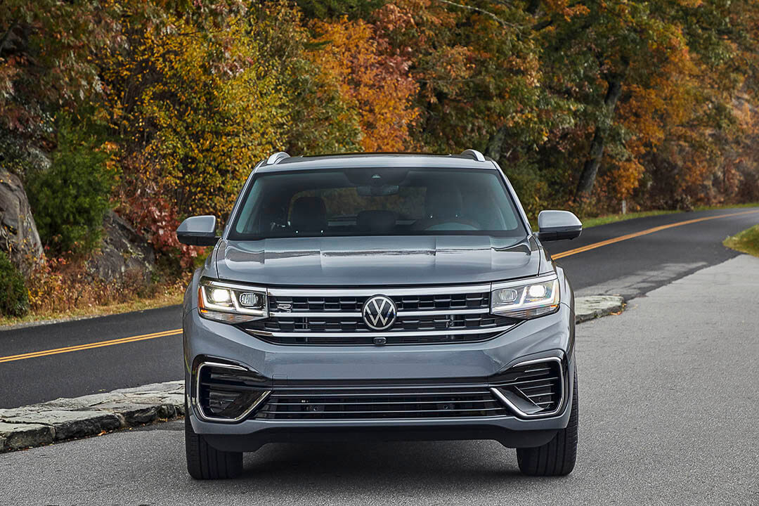 Vue avant d'un VW Atlas Cross Sport 2022 avec ses phares allumés garé sur une route
