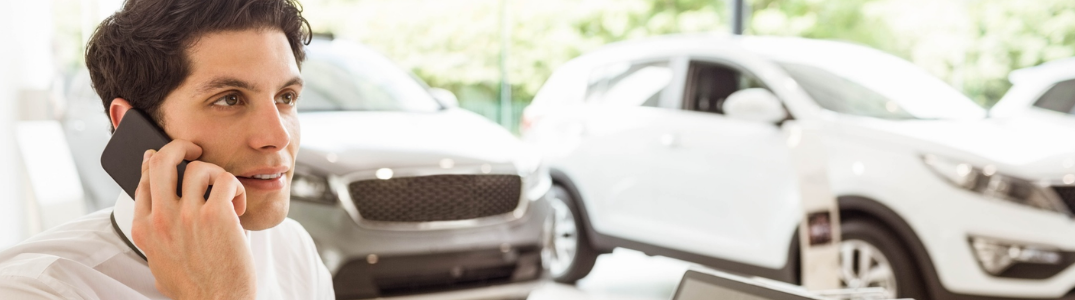 A man on his phone at a car dealership