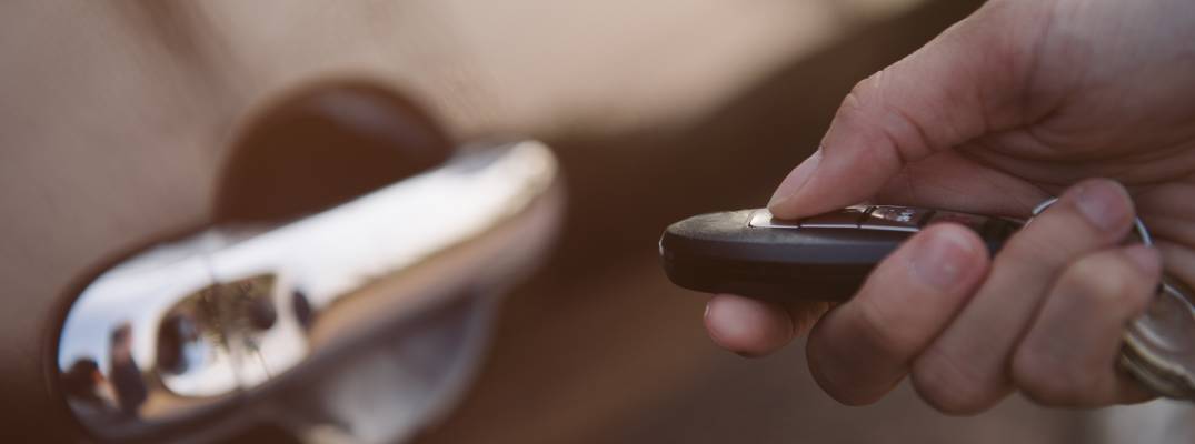 Unknown person pointing key towards car door. 