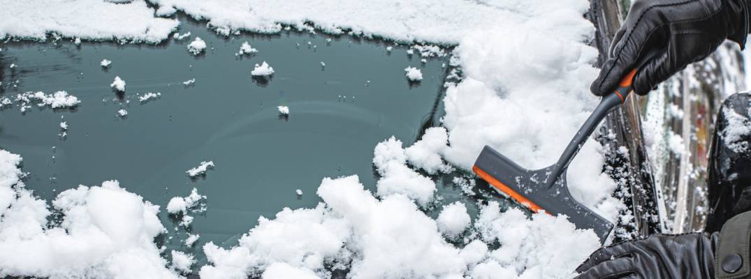 Person clearing snow from windshield  