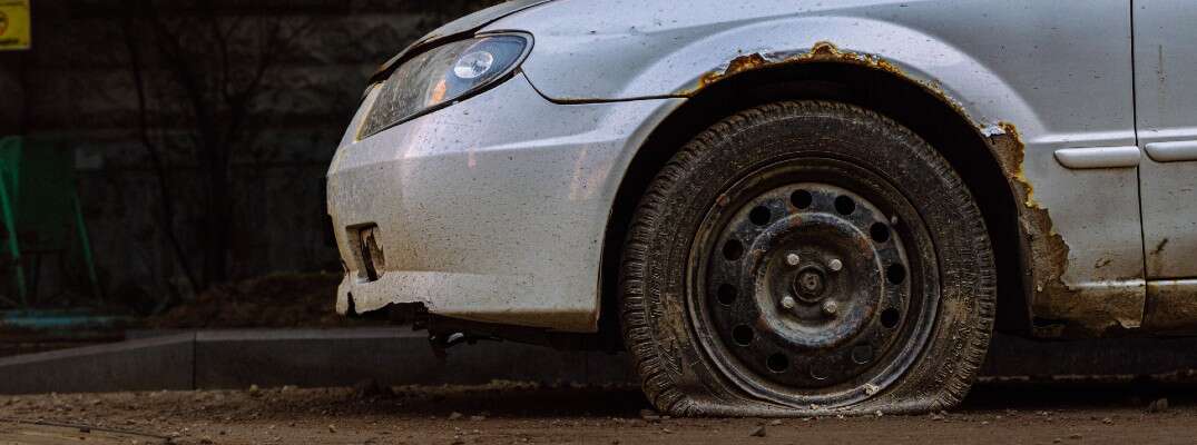 A stock photo of an old car in a junk yard.