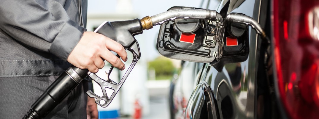 A stock photo of a person filling their car with gas.