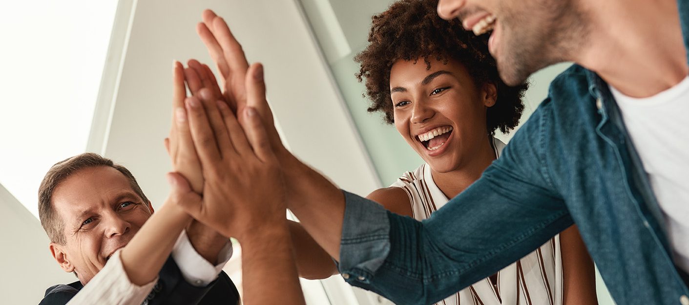 Celebrating success. Business people giving each other high-five and smiling while working together in the modern office. Teamwork