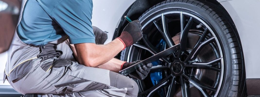 A technician inspects a wheel of a car.
