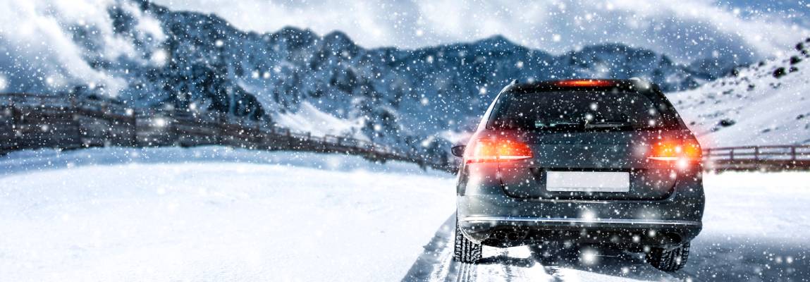 An SUV drives across a snowy field with its rear lights on