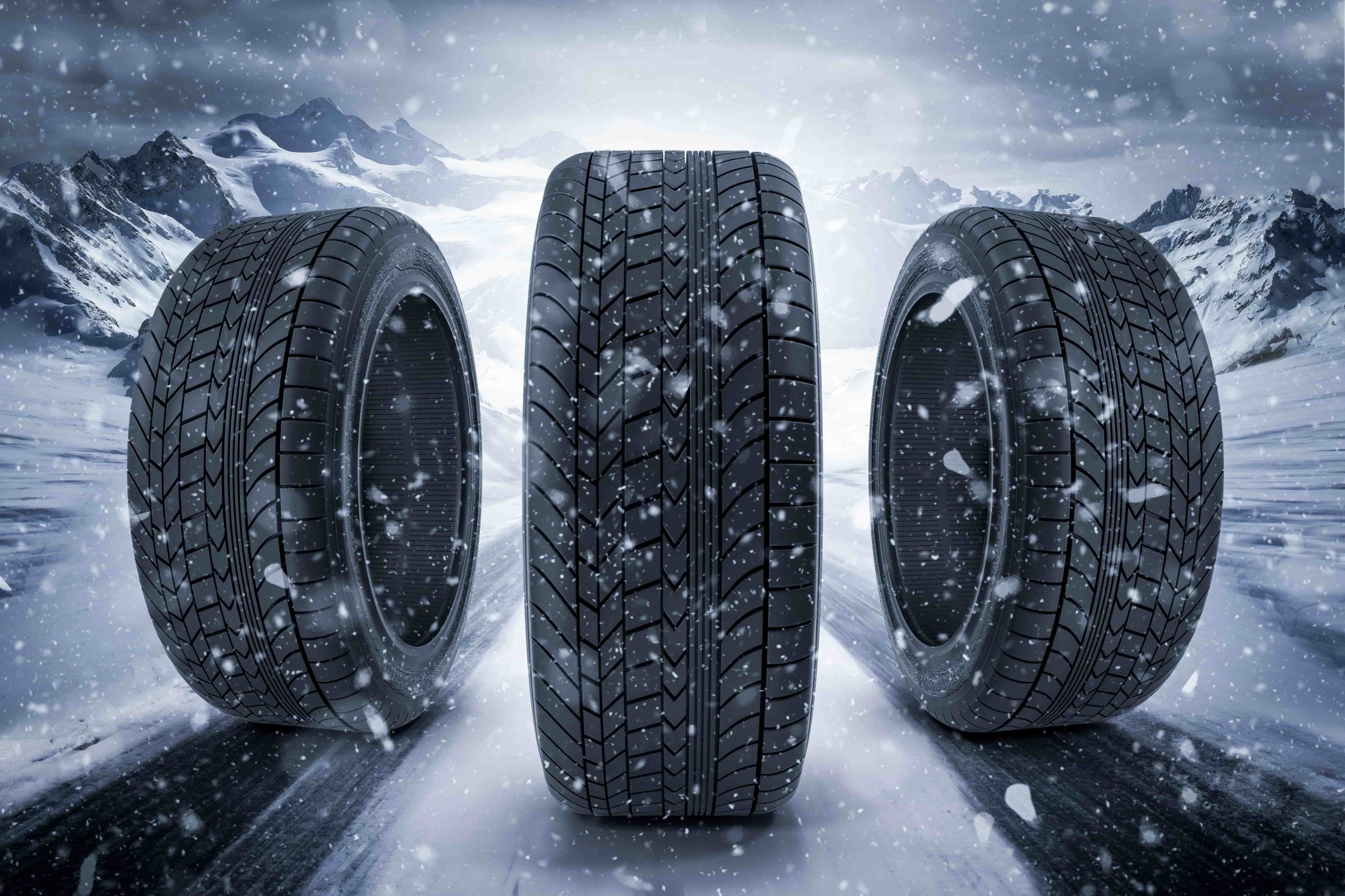 Three winter tires stand in front of a white light in the middle of a blizzard