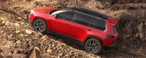 A red 2026 Jeep Cherokee climbs a rocky slope. New 2026 Jeep Cherokee Performance & Engine Guide at Blenheim Chrysler Dodge Jeep Ram