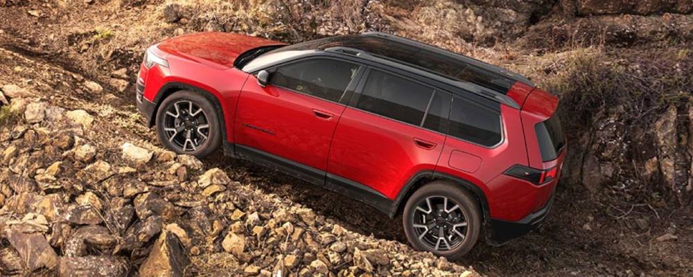 A red 2026 Jeep Cherokee climbs a rocky slope. New 2026 Jeep Cherokee Performance & Engine Guide at Blenheim Chrysler Dodge Jeep Ram