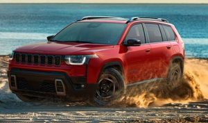 A red 2026 Jeep Cherokee kicks up dirt in front of the sea. New 2026 Jeep Cherokee Performance & Engine Guide at Blenheim Chrysler Dodge Jeep Ram