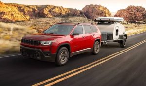 A red 2026 Jeep Cherokee pulls a silver camper. New 2026 Jeep Cherokee Performance & Engine Guide at Blenheim Chrysler Dodge Jeep Ram