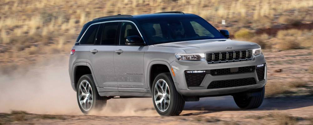 A silver 2026 Jeep Grand Cherokee drives across off-road terrain. New 2026 Jeep Grand Cherokee performance & engine guide at Blenheim Chrysler Dodge Jeep Ram in Blenheim, ON