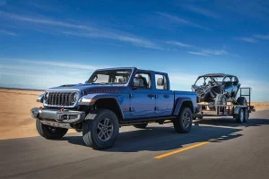 a 2026 jeep gladiator hauls a vehicle on a flatbed trailer