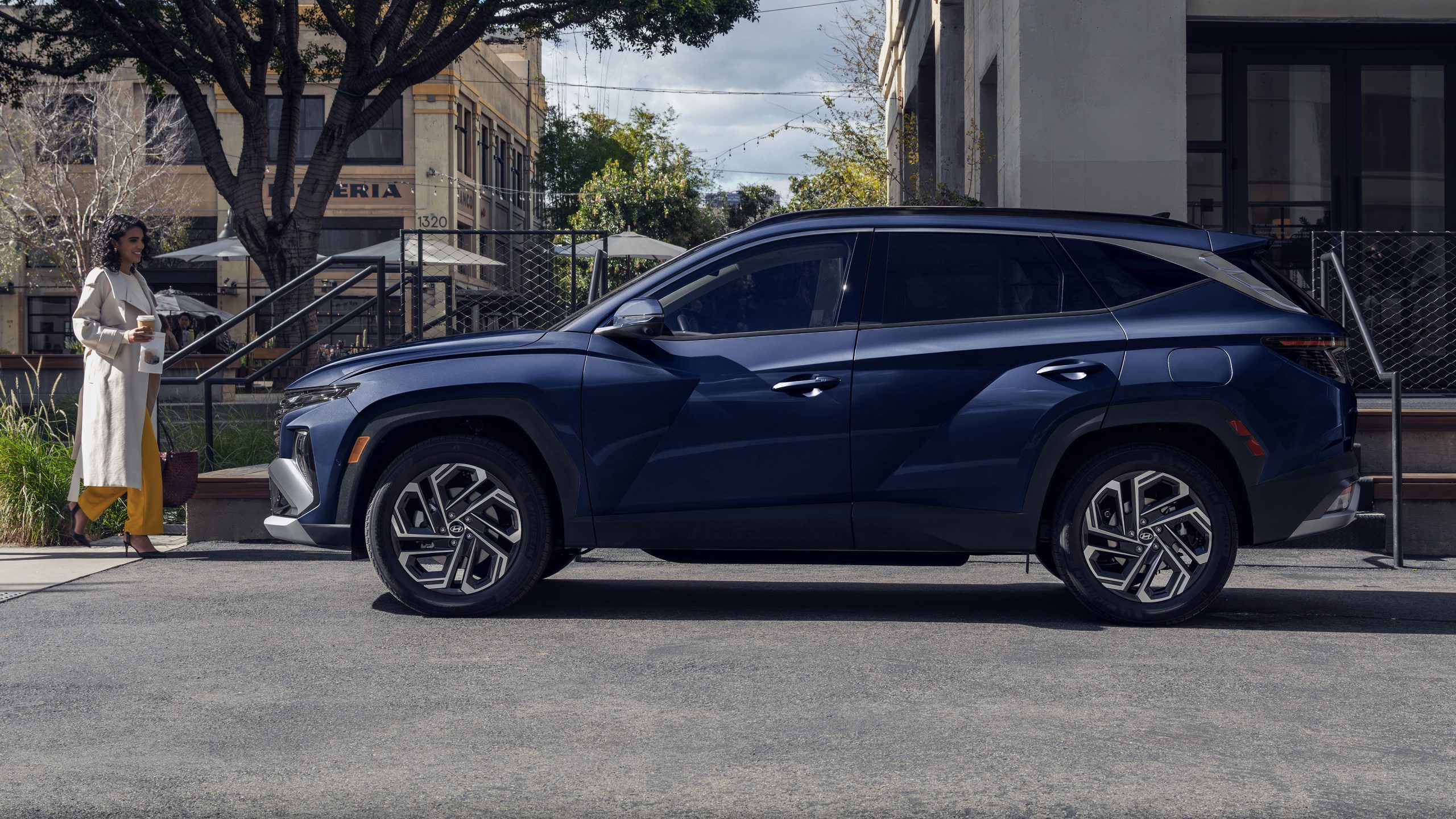 2026 Hyundai Tucson Hybrid parked side view with person approaching it