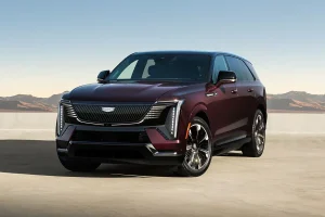 A red 2026 Cadillac Escalade IQ parked outside with mountains in the distance