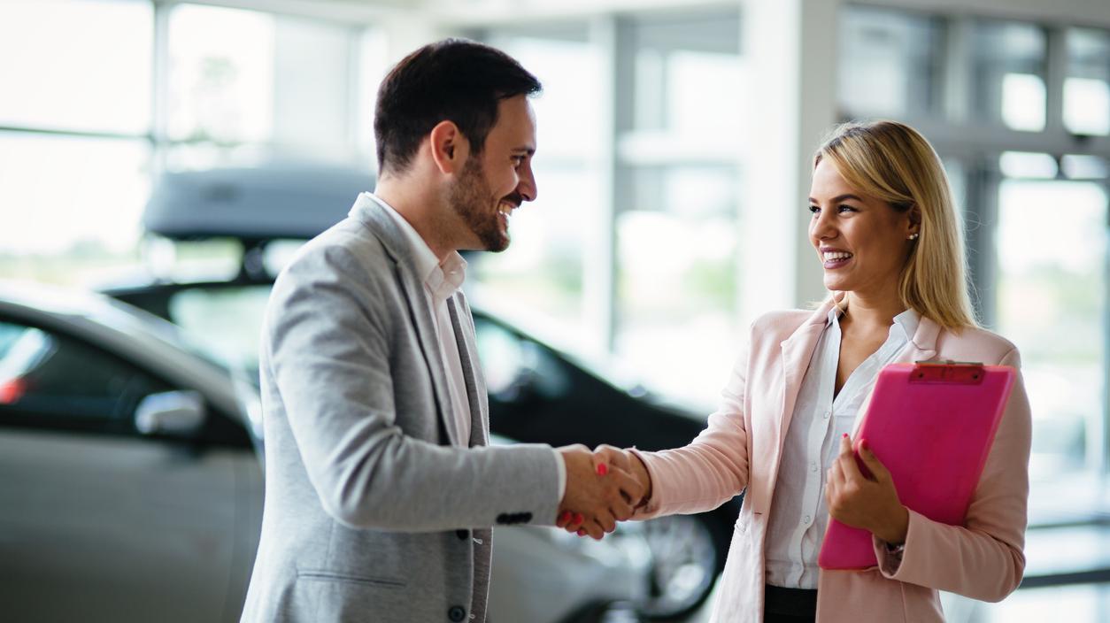 Young beautiful female car sales consultant working in showroom