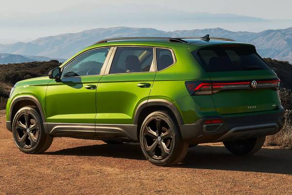 A green 2025 Volkswagen Taos photographed at an angle from behind with the mountainous horizon in the background