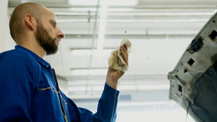 A mechanic takes a look at a dip stick during a maintenance check.
