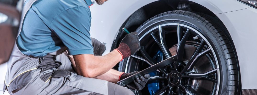 A trained technician checks over a car's tire.