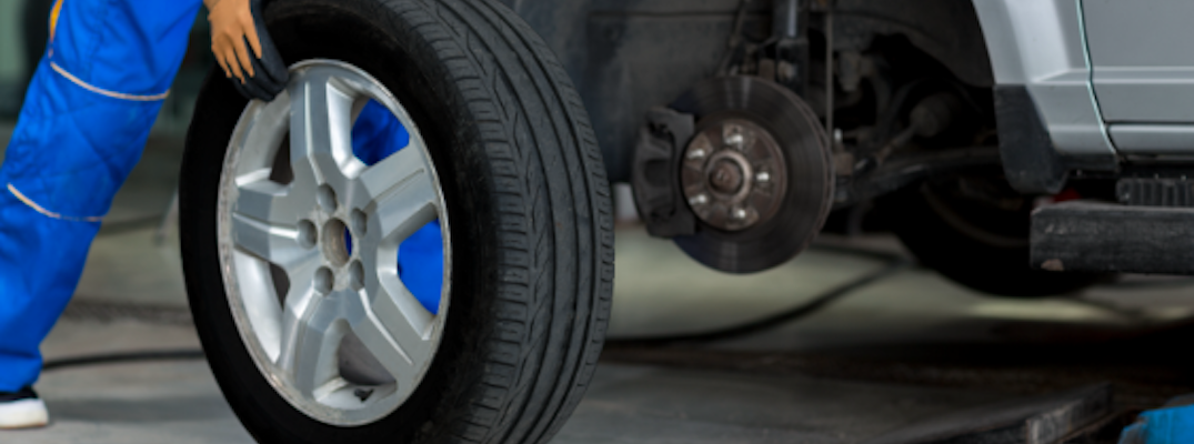 A trained technician carefully removes a tire from a vehicle.