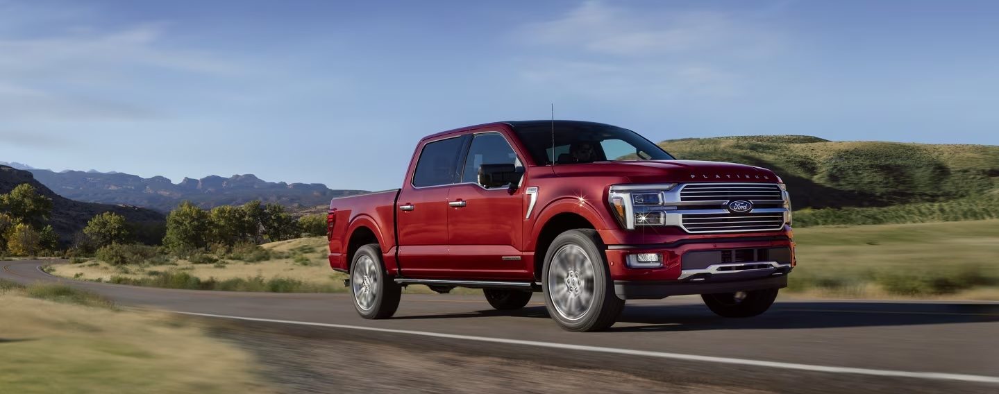 2025 F-150 driving on road surrounded by greenery during the day.