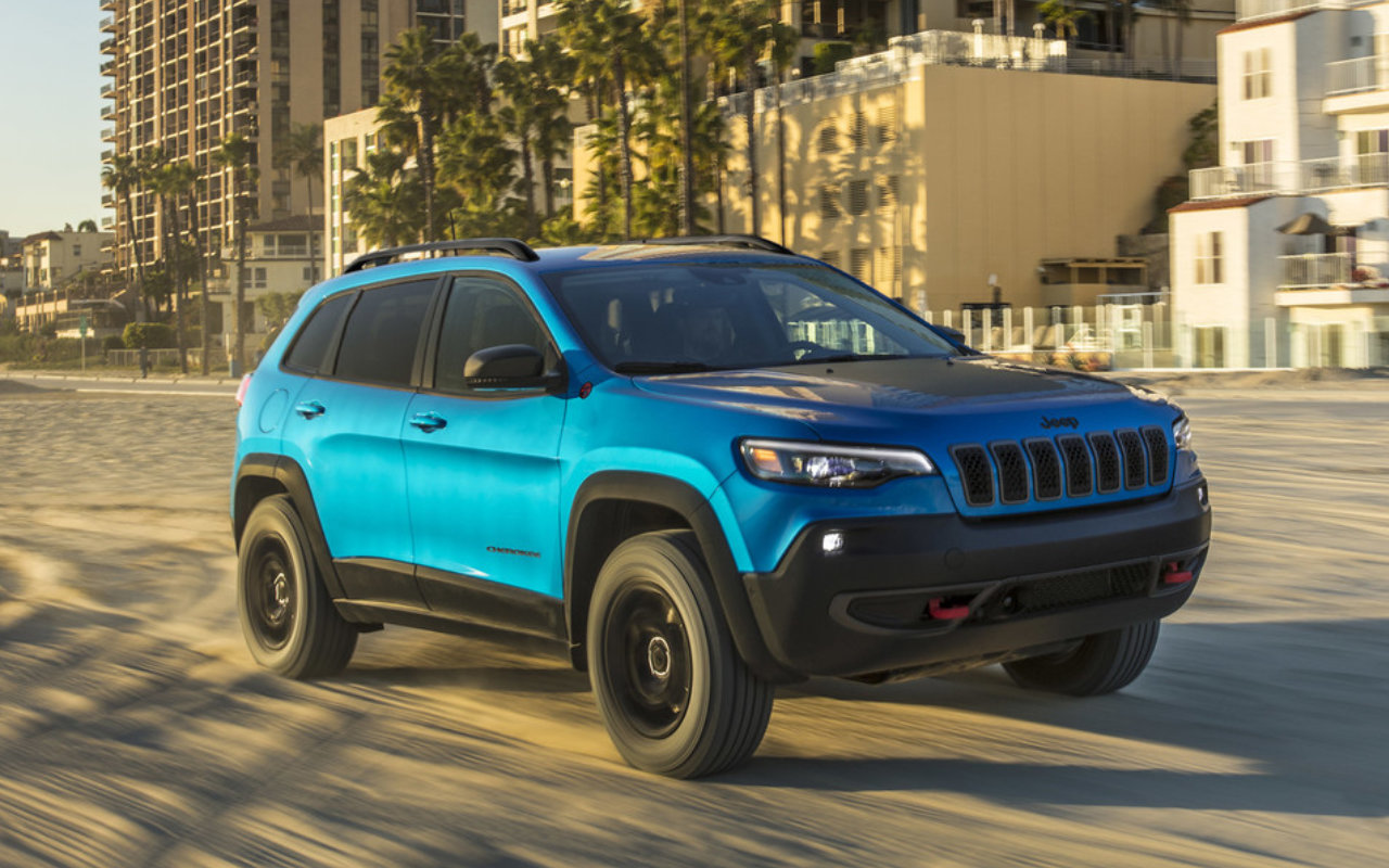 front side view of a 2023 Jeep Cherokee on a beach lined with palm trees