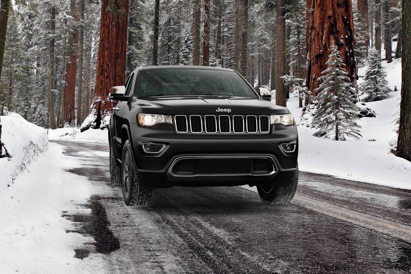 Un Jeep Grand Cherokee WK 2022 de teint noir étincelant roulant sur une route pendant la saison hivernale