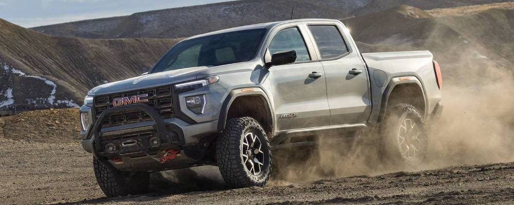 A 2026 GMC Canyon speeds over the off-road, kicking up dirt clouds. New 2026 GMC Canyon pickup truck performance specs and towing capacity at College Park GM in Vermilion, AB