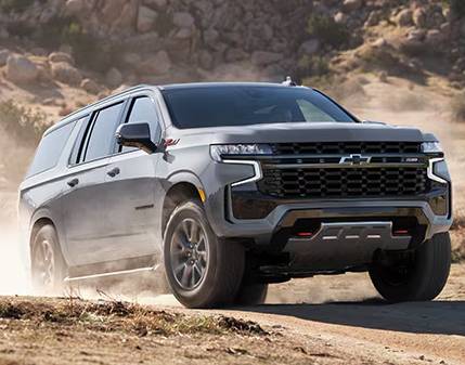 A grey 2025 Chevrolet Suburban drives across the off-road kicking up dirt