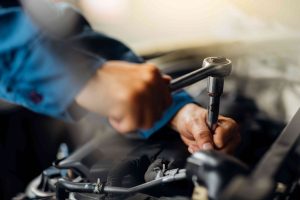 mechanic tightens bolt with a wrench in a vehicle engine