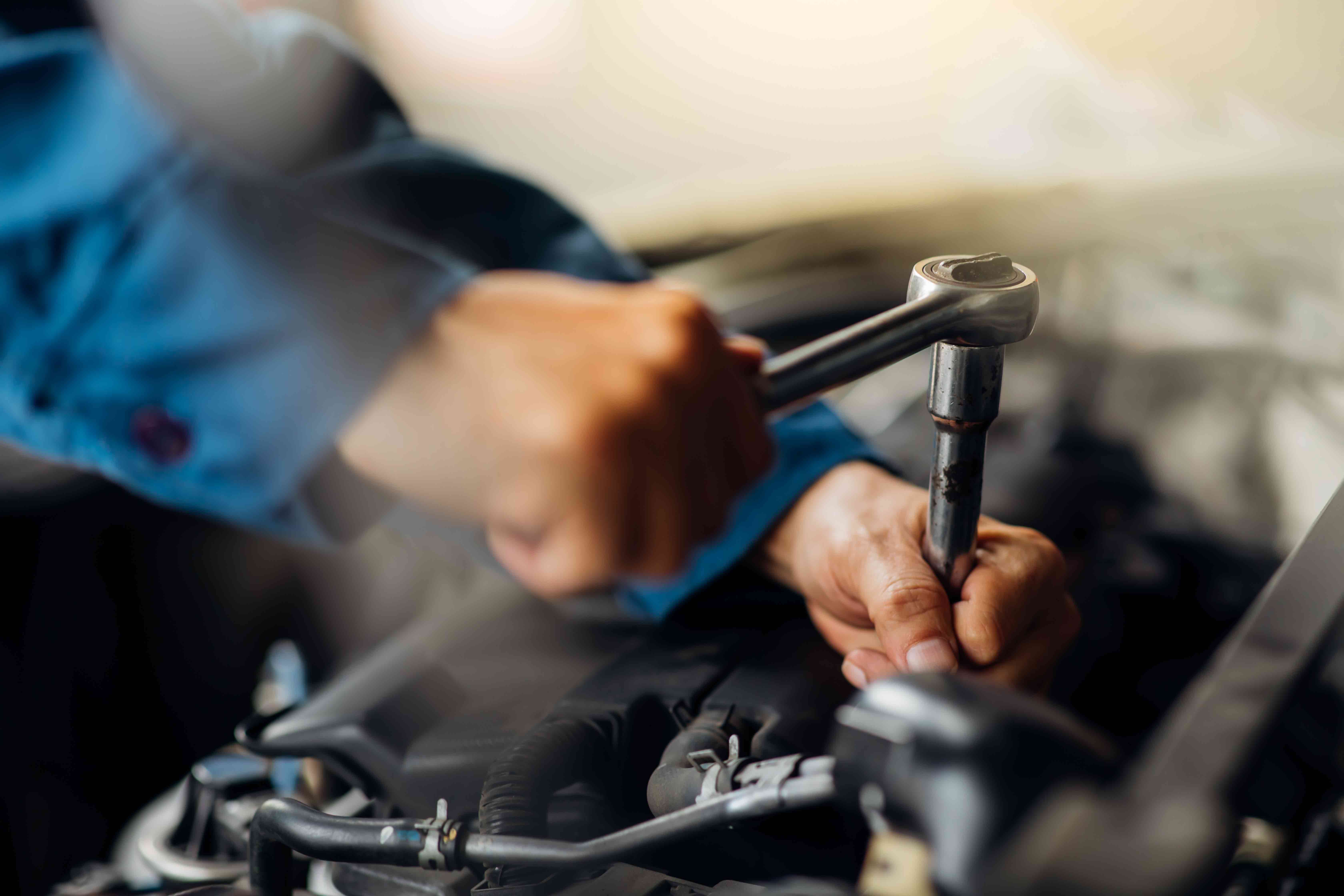 mechanic tightens bolt with a wrench in a vehicle engine