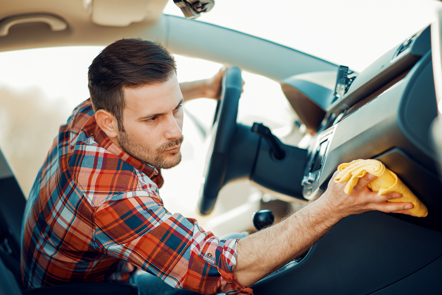 Young worker cleaning car dashboard.