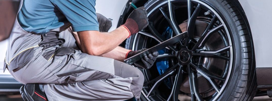 A mechanic inspects the wheel well of a vahicle.