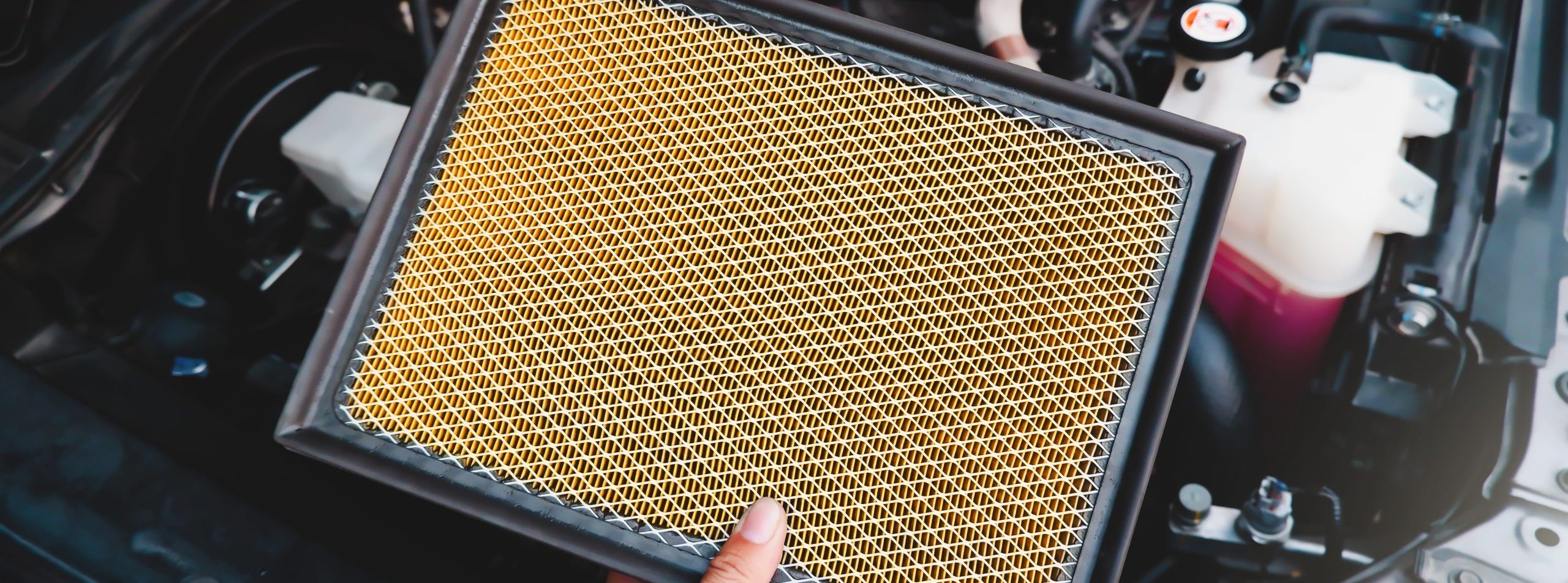 A auto mechanic carries a replacement car air filter for car engine maintenance