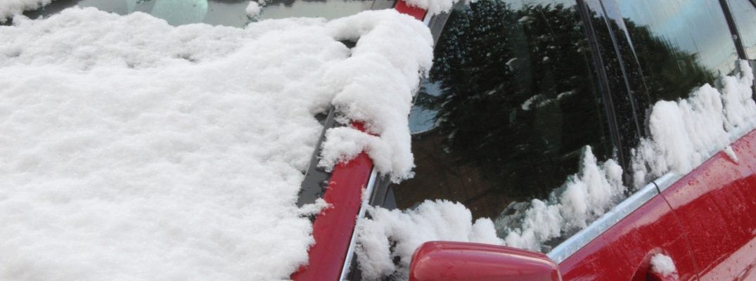 A red car from the front that is covered in snow.