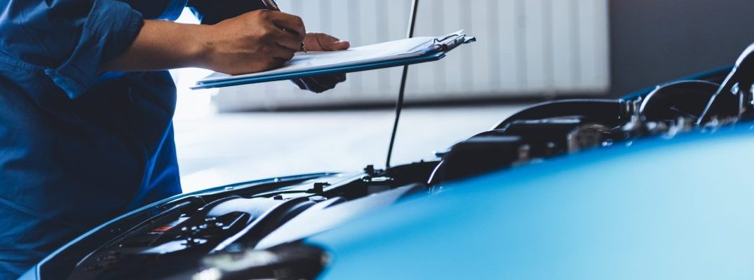 A mechanic takes a look under the hood of a vehicle.