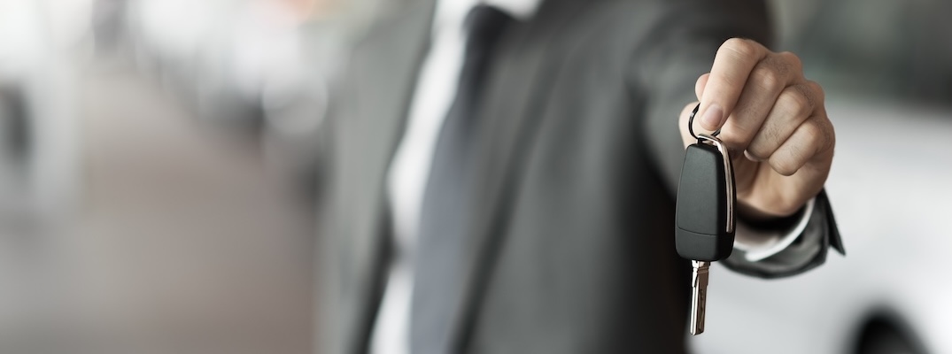 A salesman holds out a set of keys to a new Hyundai.