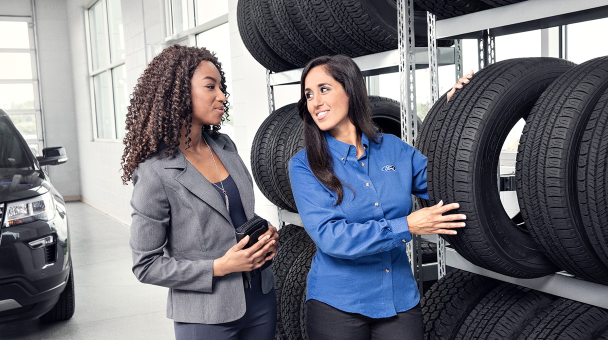 Two people standing near rack of tires
