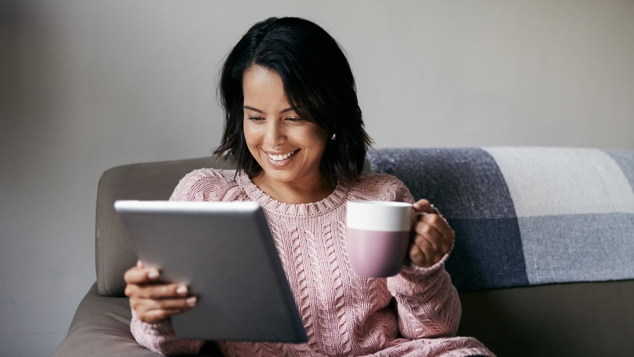 Unknown person using tablet and holding mug