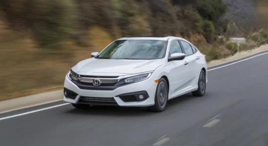 White Honda Civic driving on a winding road with hills in the background, featured by Driven Auto Group Newmarket.