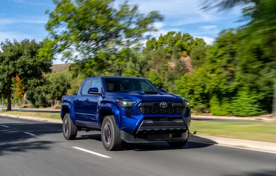 Blue Toyota Tacoma pickup driving on a city road, showcasing durability and strong resale appeal as the Toyota Tacoma - King of Resale Value at Driven Auto Group Newmarket.