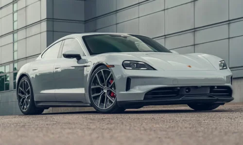 2026 Porsche Taycan electric luxury sedan parked outside a modern building, featured by DRIVEN Newmarket as a high-performance EV.