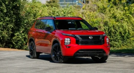 2026 Nissan Rogue in red parked outdoors with greenery in the background, featured by DRIVEN Newmarket as a modern compact SUV for Canadian drivers.