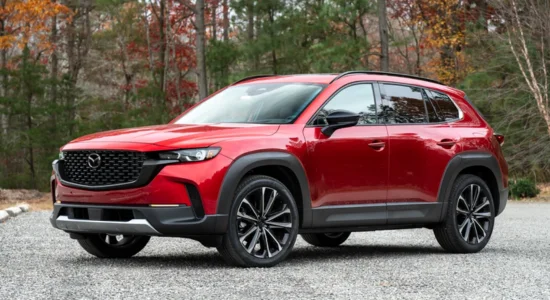 2026 Mazda CX-50 in red parked on gravel with autumn trees in the background, featured by DRIVEN Newmarket as a rugged and stylish SUV.
