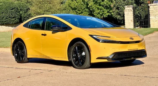 2026 Toyota Prius hybrid hatchback in yellow parked outdoors on a sunny day, featured by DRIVEN Newmarket as a fuel-efficient hybrid car.