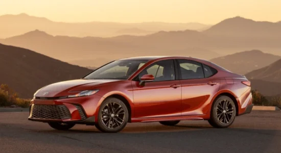 2026 Toyota Camry sedan in red parked on a scenic mountain road at sunset, featured by DRIVEN Newmarket as a reliable midsize sedan for Canadian drivers.
