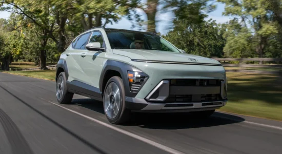 2026 Hyundai Kona Hybrid compact SUV driving on a tree-lined road, featured by DRIVEN Newmarket as an efficient hybrid option for Canadian drivers.