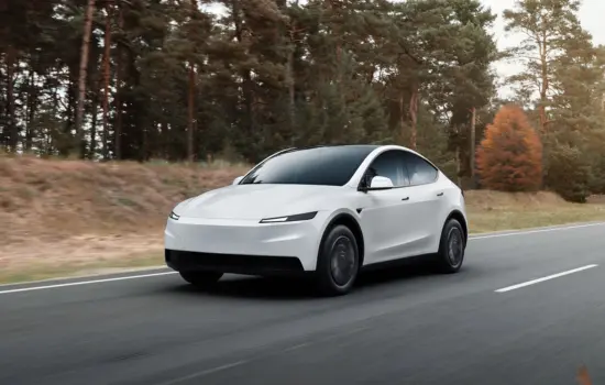 White Tesla Model Y (2021 and newer) electric SUV driving on a scenic road, featured by DRIVEN Newmarket.